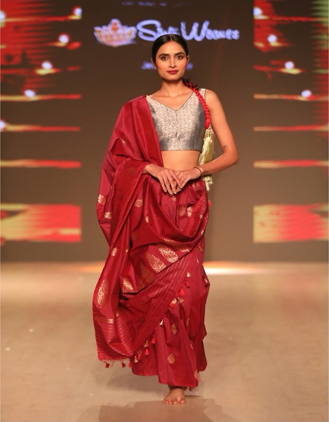 A model in a red Banarasi silk saree with gold butis, on the runway