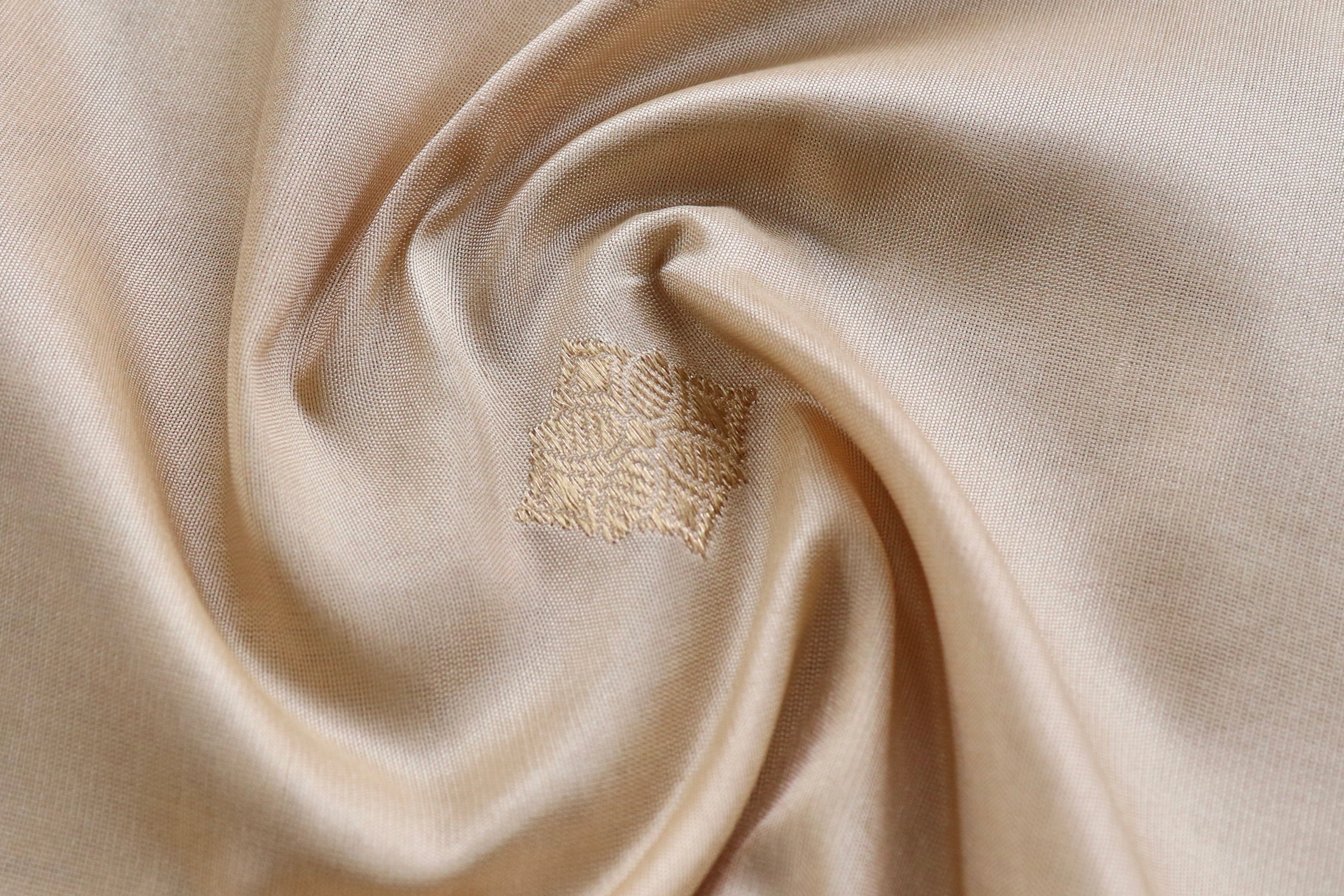 A cream Banarasi spread open in a loose swirl, resting